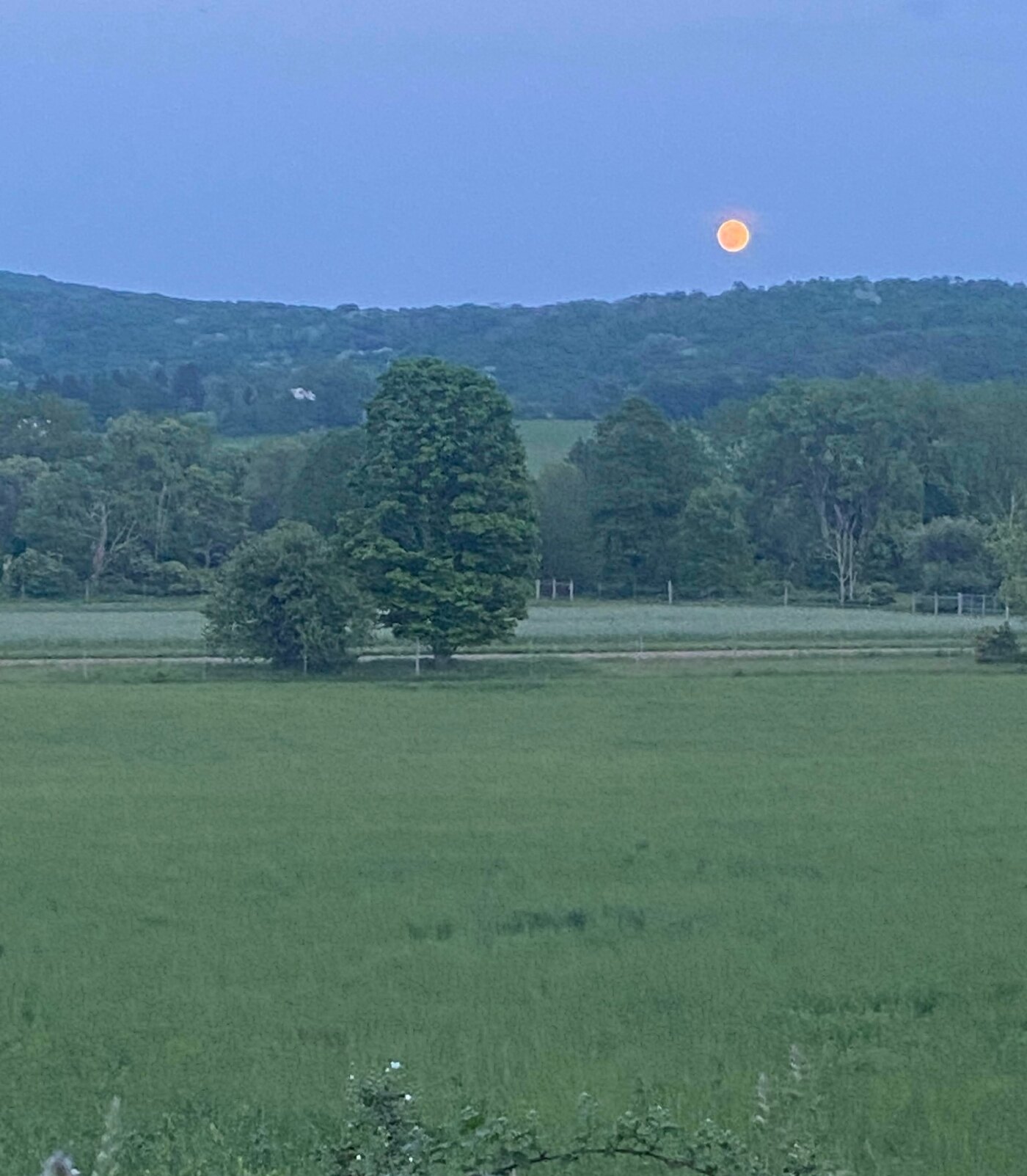 Moon rising over a Columbia County hillside above a field